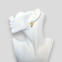 Charger l&#39;image dans la galerie, Petites boucles d&#39;oreilles pendantes, de forme demi-lune, en métal martelé doré à l&#39;or fin et perles de Pyrite, portées à l&#39;oreille sur un buste blanc
