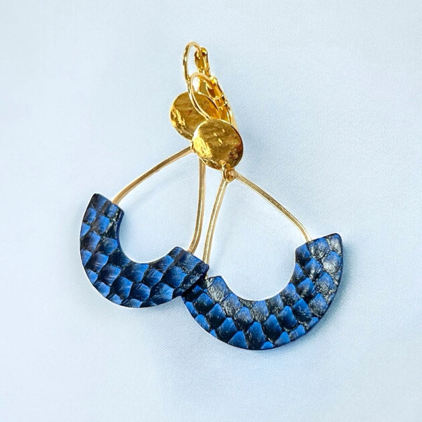 Boucles d'oreilles Anoush de Nune, dorées à l'or fin avec cuir marin, cuir de poisson saumon bleu saphir écaille, en forme de demi-lune, sur fond gris