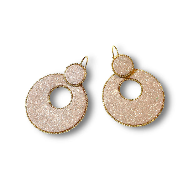 boucles d'oreilles créoles Nune modèle Céleste en forme de cercles en cuir rose pailleté argent cerclées de chaîne dorée, sur fond blanc