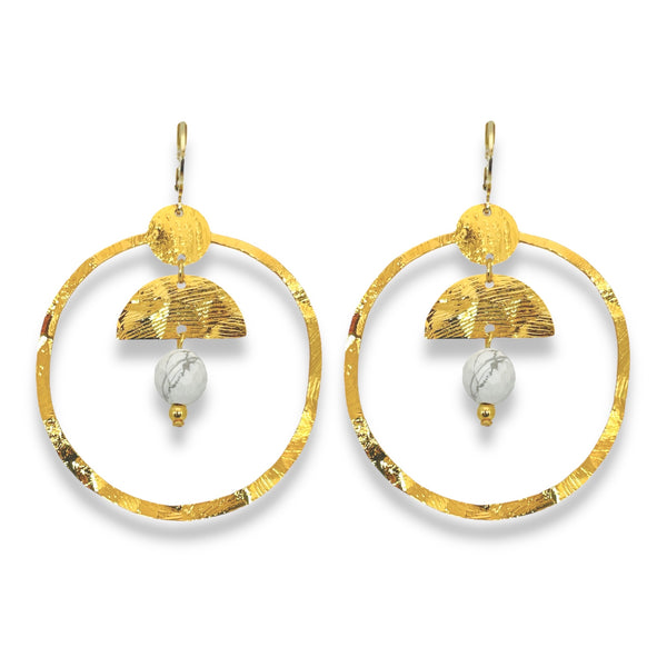 Grandes boucles d'oreilles créoles en métal martelé doré à l'or fin et pierres naturelles howlite blanche accrochée à une demi-lune, sur fond blanc