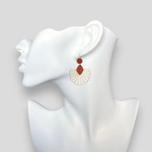 Charger l&#39;image dans la galerie, Grandes boucles d&#39;oreilles dorées en forme d&#39;éventail style art déco, avec empiècements de cuir terracotta, portées à l&#39;oreille sur un buste blanc

