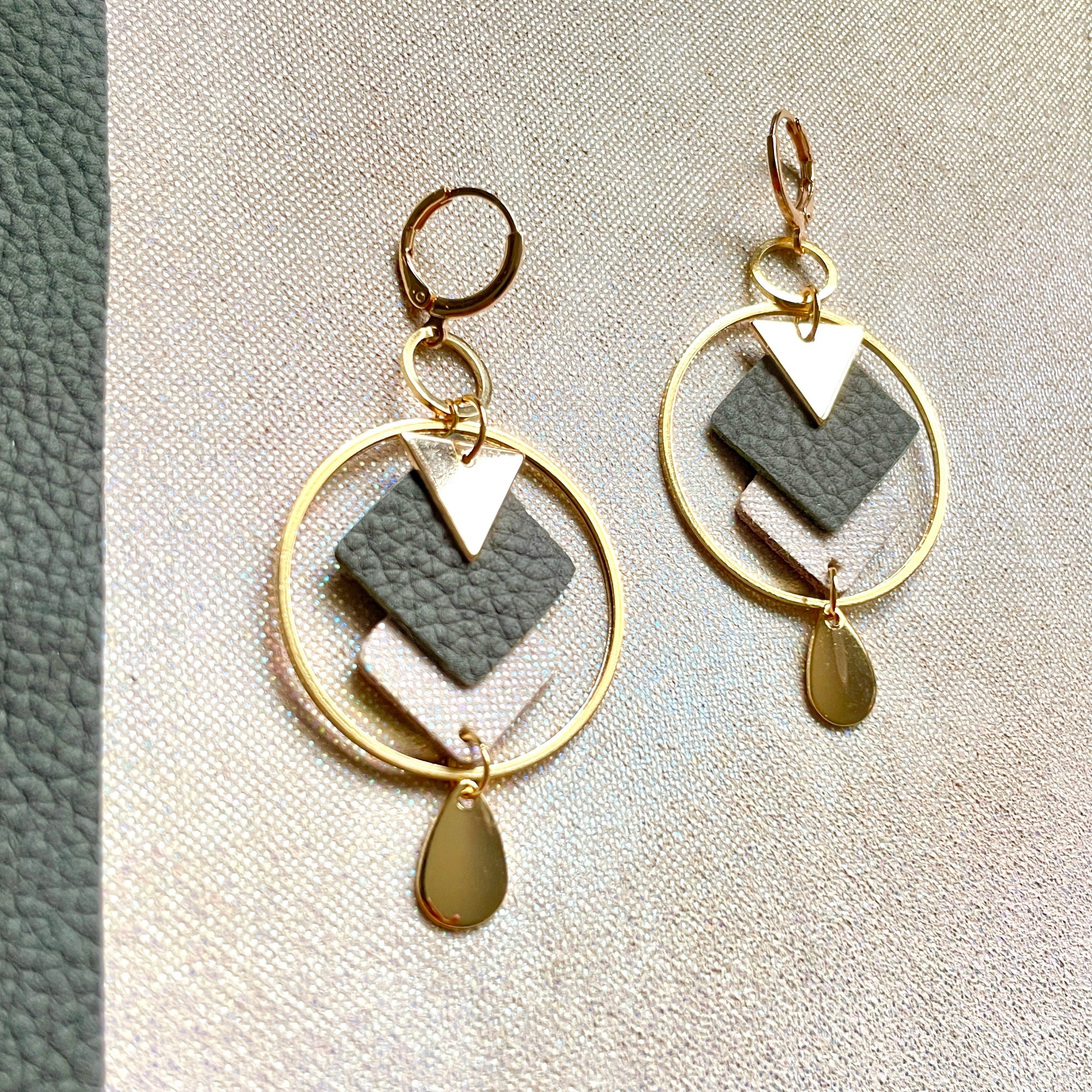 Boucles d'oreilles Nune modèle Créoles Adamante Or en cuir kaki gris grainé et laiton doré à l'or fin sur fond beige irisé