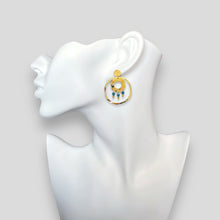 Charger l&#39;image dans la galerie, Grandes boucles d&#39;oreilles puces créoles dorées pendantes longues rondes avec double anneau et petites perles en apatite bleue, portées à l&#39;oreille sur un buste blanc
