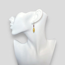 Charger l&#39;image dans la galerie, Boucles d&#39;oreilles fines en pointe en métal martelé doré à l&#39;or fin et petites perles de grenat, portées à l&#39;oreille sur un buste blanc
