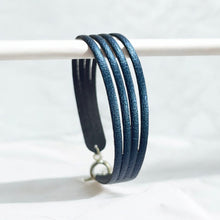 Charger l&#39;image dans la galerie, Bracelet en cuir doré bleu nuit métallisé à 4 liens avec petite boucle argentée, sur fond blanc
