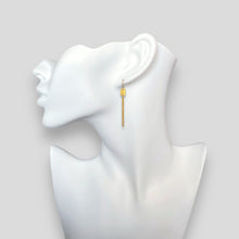 Charger l&#39;image dans la galerie, Fines boucles d&#39;oreilles pendantes en métal martelé doré à l&#39;or fin avec pendant rectangulaire et chainette, portées aux oreilles sur un buste blanc
