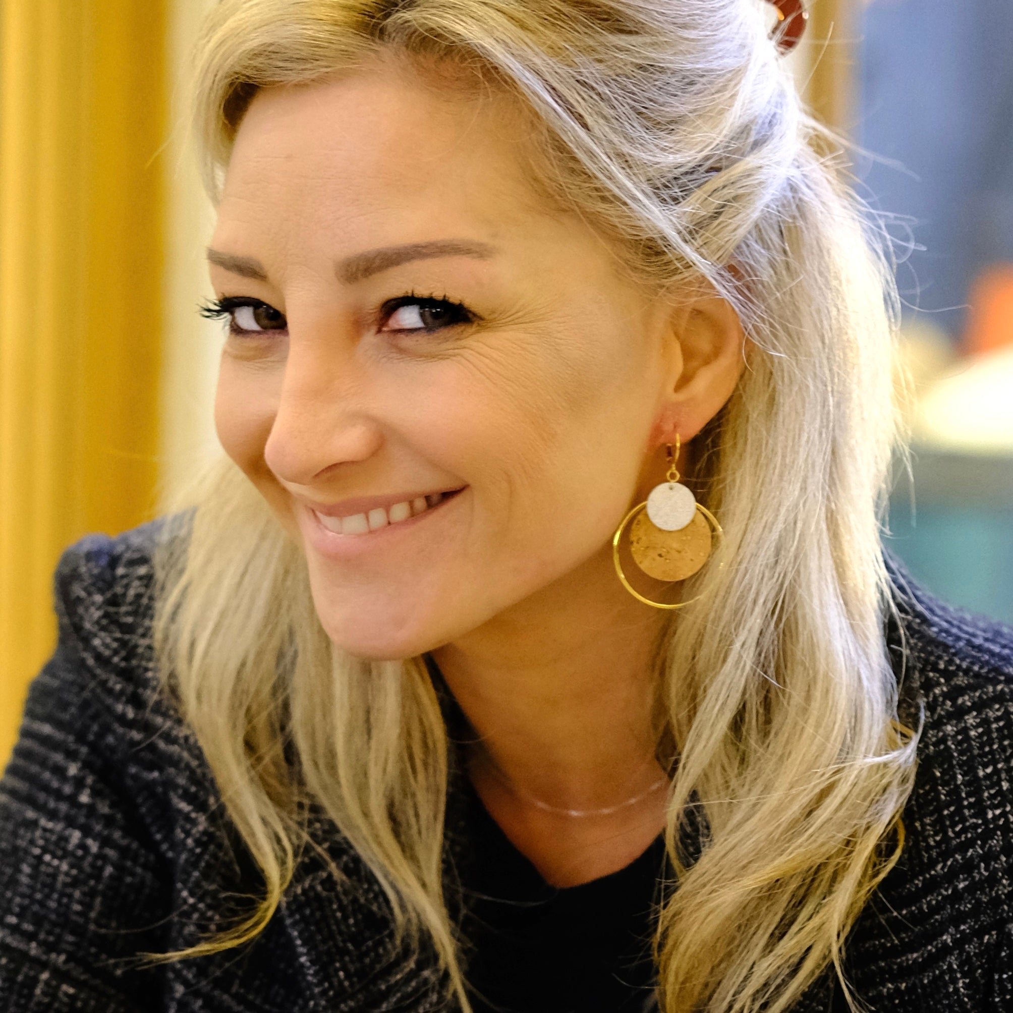 Femme blonde portant des Boucles d'oreilles dorées rondes en liège brut et argent, soulignées par de grands anneaux dorés