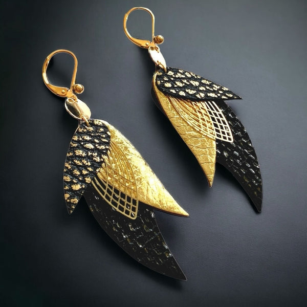boucles d'oreilles dorées Nune modèle Ara en plumes de cuirs noir brillant façon serpent, doré brillant et noir grainé or, sur fond noir