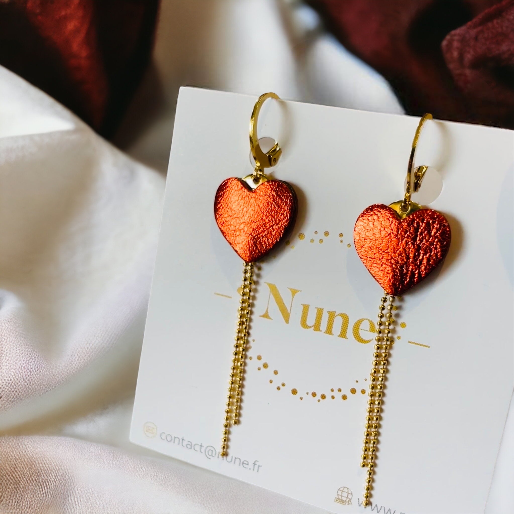 fines boucles d'oreilles dorées, petits cœurs de cuir recyclé orange sanguine métallisé et chaînettes, sur fond blanc