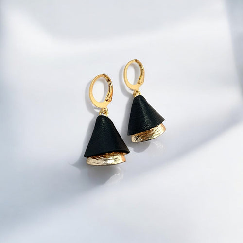 Petites boucles d'oreilles dorées pendantes en forme de clochettes, en cuir bicolore noir et doré clair froissé, sur fond blanc ombragé