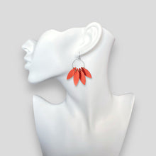 Charger l&#39;image dans la galerie, Grandes et longues boucles d&#39;oreilles argentées en forme de couronne de plumes, en cuir orange carotte, portées à l&#39;oreille sur un buste blanc
