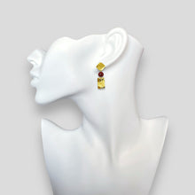 Charger l&#39;image dans la galerie, Petites boucles d&#39;oreilles puces en métal martelé dorée et perles de Mokaïte acajou, de forme losanges et rectangles, portées à l&#39;oreille sur un buste blanc

