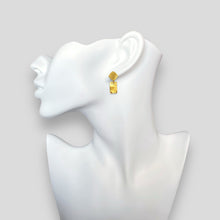 Charger l&#39;image dans la galerie, Petites puces d&#39;oreilles losanges avec pendant rectangulaire en métal martelé doré à l&#39;or fin, portées aux oreilles sur un buste blanc
