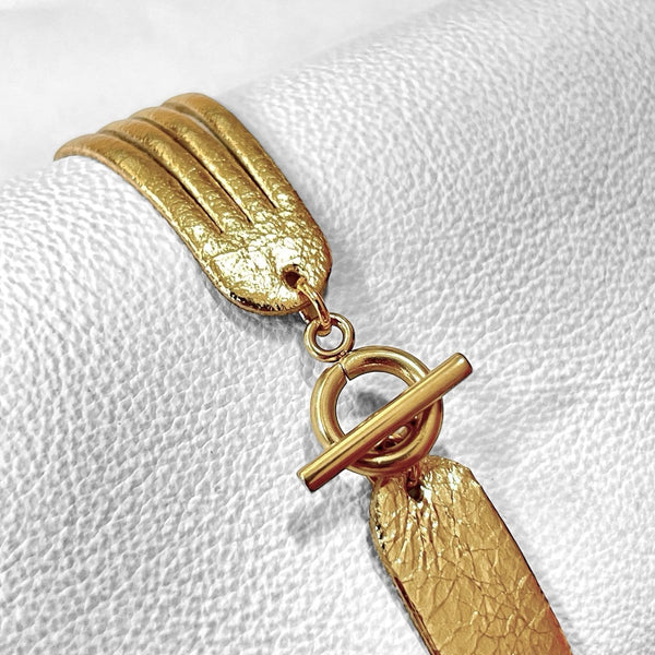 Bracelet en cuir doré brillant à 4 liens avec petite boucle dorée, vu de dessous, sur fond blanc