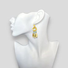 Charger l&#39;image dans la galerie, Longues boucles d&#39;oreilles en métal martelé doré à l&#39;or fin et perles d&#39;amazonite de style éthnique, portées à l&#39;oreille sur un buste blanc
