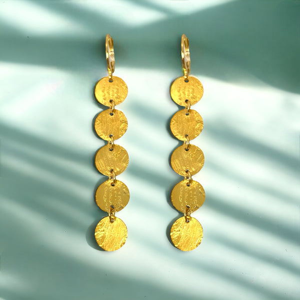 Fines longues boucles d'oreilles dorées pendantes en chapelet de 5 petits sequins ronds, sur fond vert ombragé