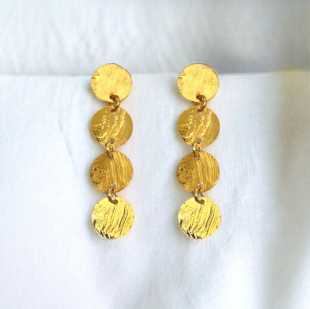 Fines puces d'oreilles pendantes en chapelet de 4 petits sequins ronds en métal martelé doré à l'or fin, sur un tissu blanc