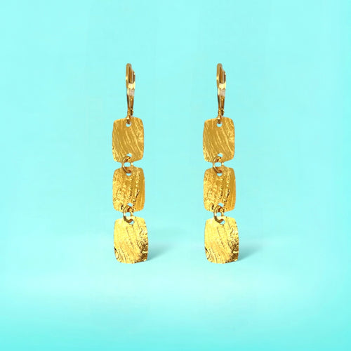 Fines boucles d'oreilles dorées pendantes en chapelet de 3 petits rectangles, sur fond bleu