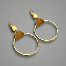 Charger l&#39;image dans la galerie, boucles d&#39;oreilles dorées avec grands anneaux créoles attachés par de fines pièces de liège brut, sur fond gris
