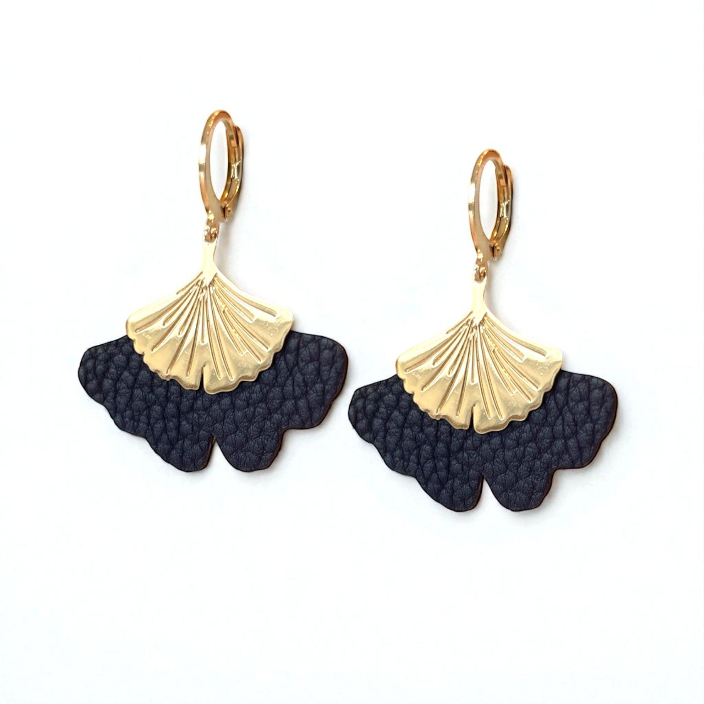 Boucles d'oreilles dorées pendantes en cuir bleu nuit grainé en forme de gingko, sur fond blanc