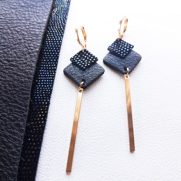 Boucles d'oreilles dorées Nune modèle Ada en cuirs noir grainé et noir grainé irisé sur fond blanc