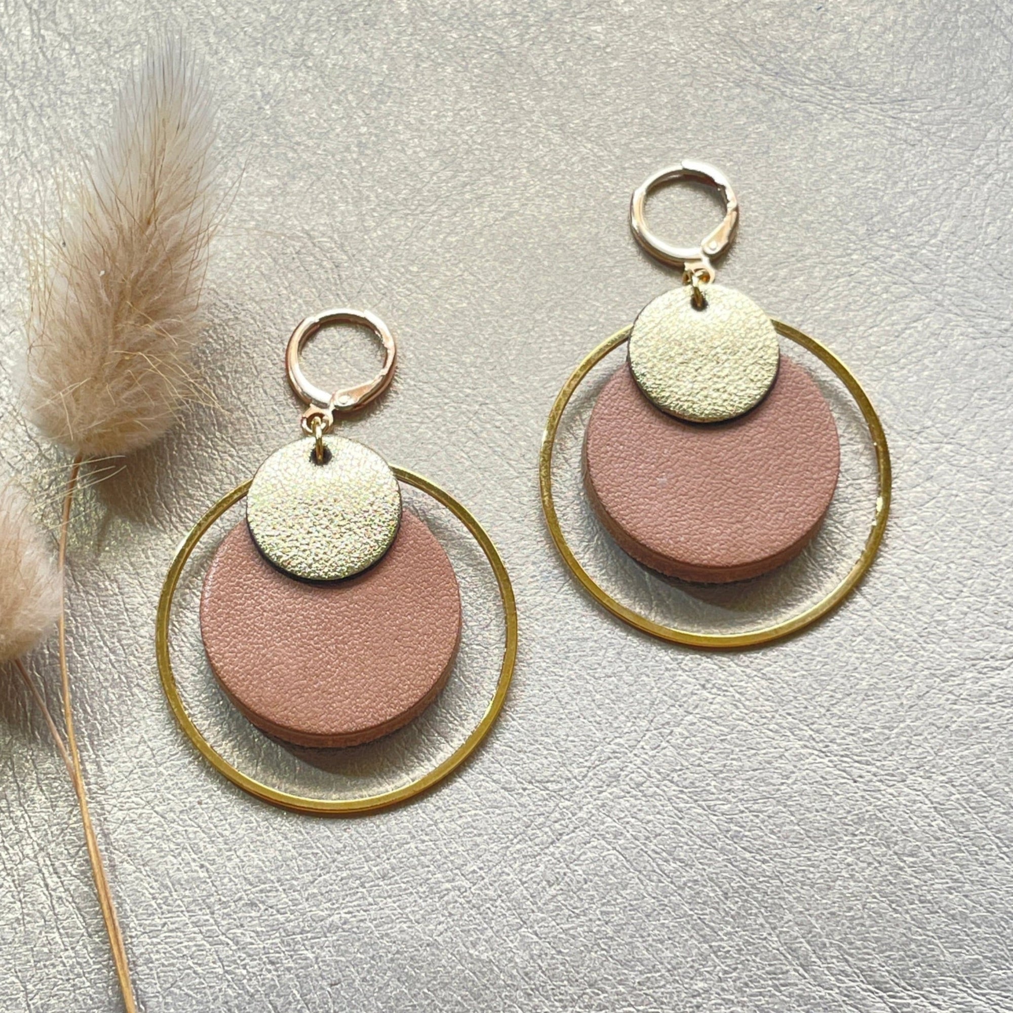 boucles d'oreilles dorées Nune modèle Danaé en cuirs beige amande et doré satiné sur fond gris doré