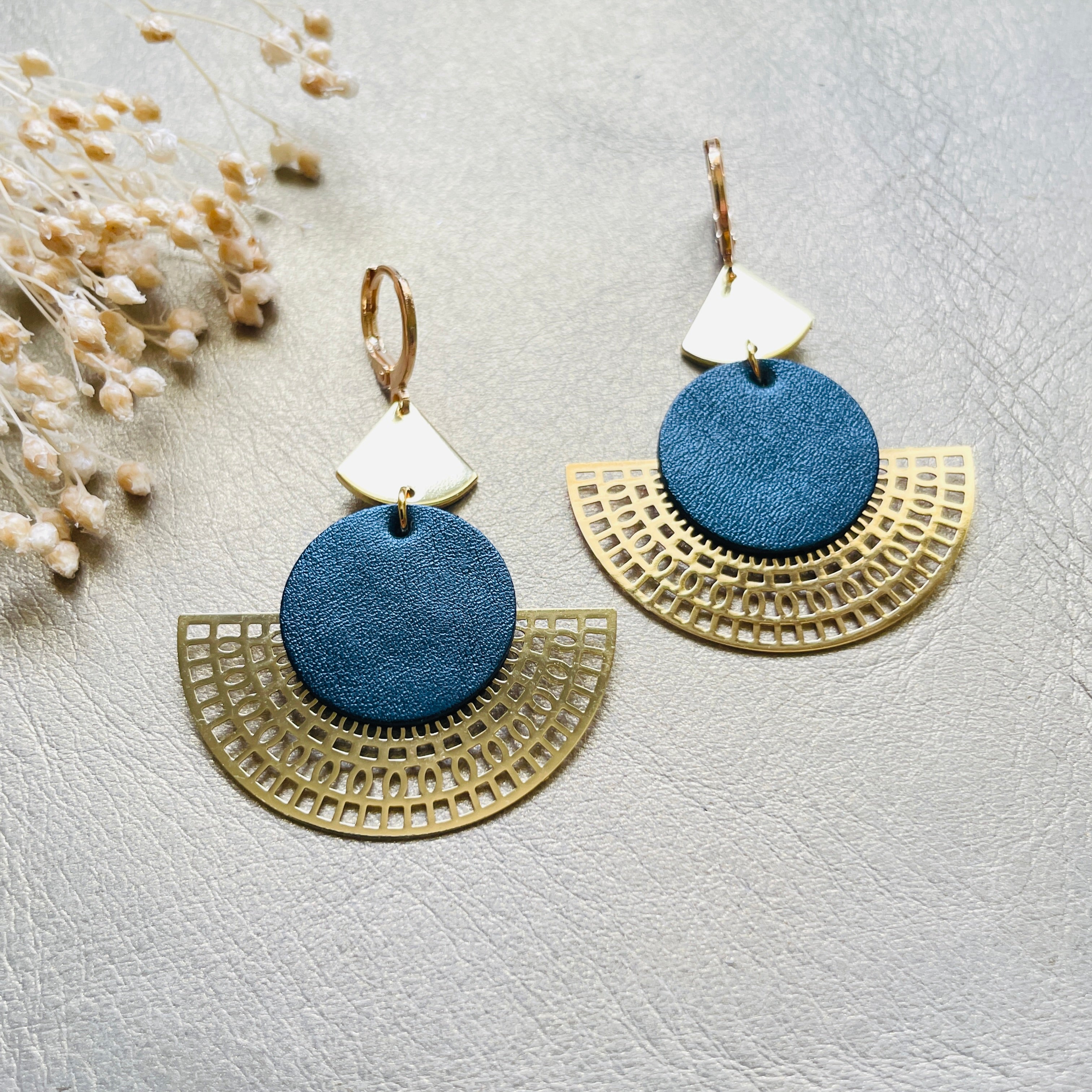 Boucles d'oreilles dorées Nune modèle Ephésia en cuir bleu nuit métallisé sur fond gris doré