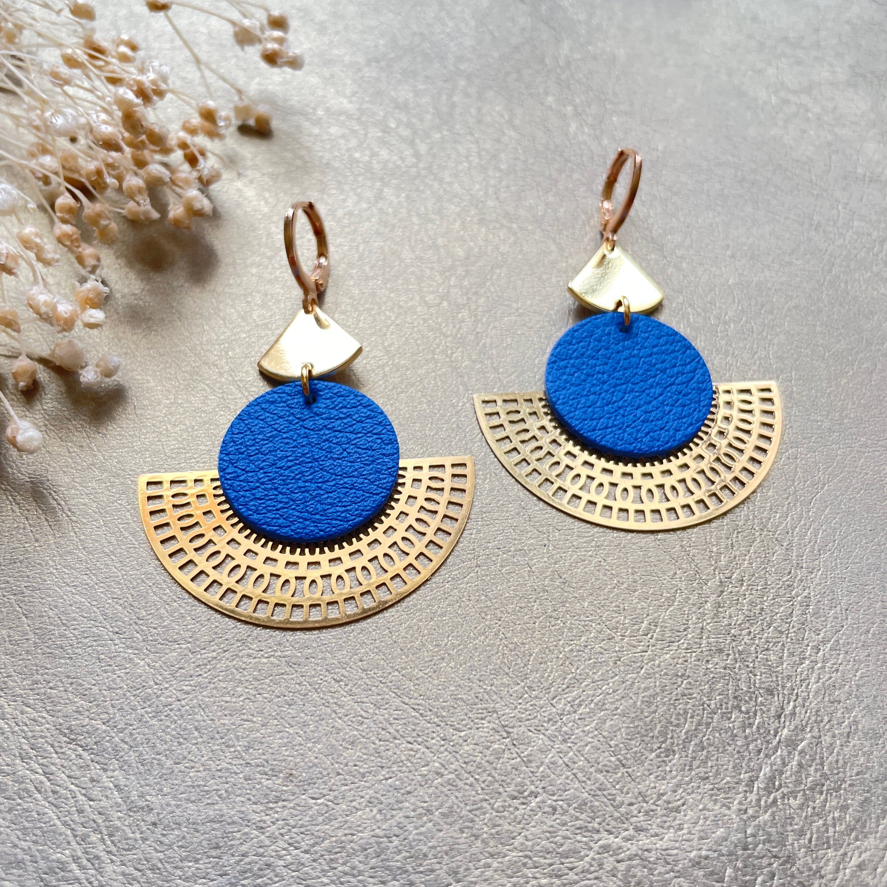 Boucles d'oreilles dorées Nune modèle Ephésia en cuir bleu roi grainé sur fond gris doré