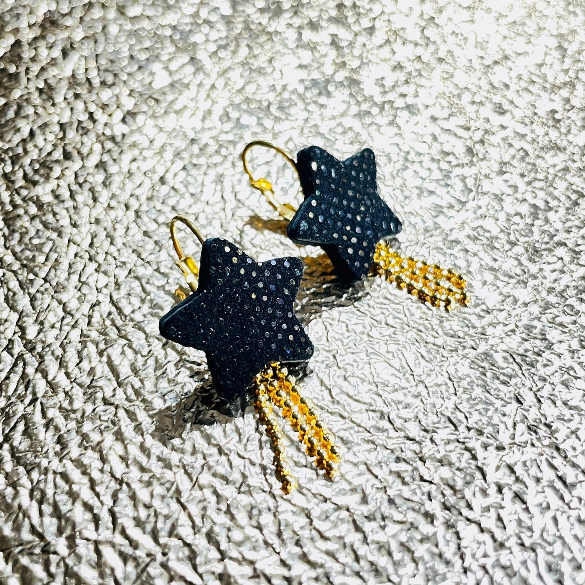 Boucles d'oreilles dorées Stella en forme d'étoiles, en cuir noir grainé irisé, sur fond argent