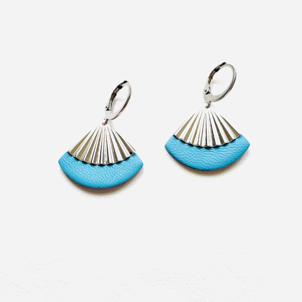 Petites boucles d'oreilles argentées Nune modèle Alya en forme d'éventail en cuir bleu ciel, sur fond cuir blanc