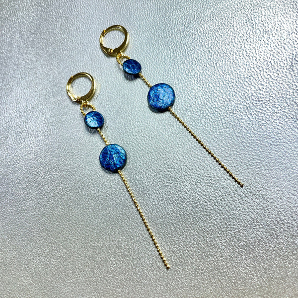 Fines boucles d'oreilles Lyre de Nune, dorées à l'or fin avec petites pastilles de cuir marin, cuir de poisson saumon bleu saphir métallisé sur chaînette dorée, sur fond gris argenté