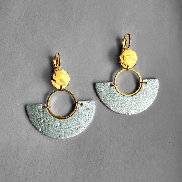 paire de boucles d'oreilles dorées en forme de demi-lunes en liège argenté, sur fond gris