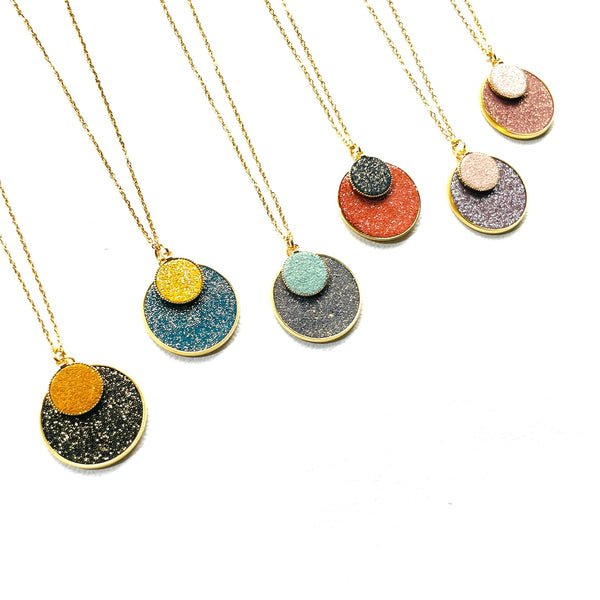 6 Colliers Bulles pailletées Nune, courts dorés avec pendentifs ronds composés de doubles sertis de cuirs pailletés, sur fond blanc