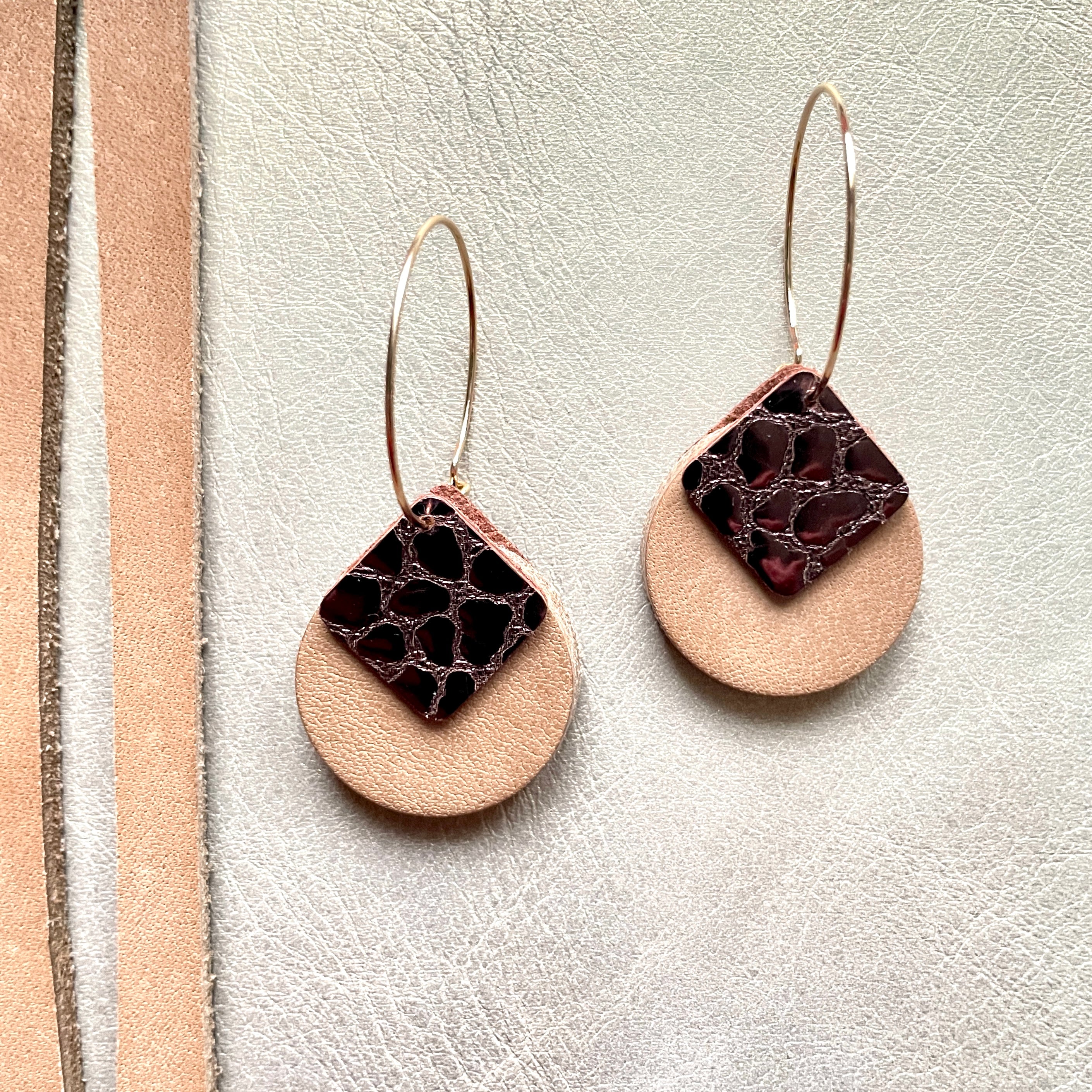 boucles d'oreilles dorées Nune modèle Héra en cuirs beige amande et chocolat brillant façon croco sur fond gris doré