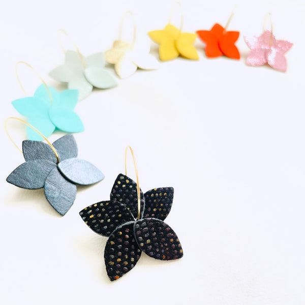 Arc en ciel de petites créoles Jasmin Nune en forme de fleurs en cuirs noir grainé irisé, bleu nuit métallisé, rouge, rose brillant, vert menthe, jaune pastel, bleu lune nacré, doré clair et argent et anneaux dorés