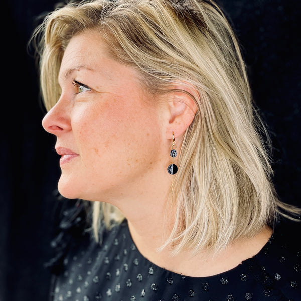 Fine boucle d'oreille Lyre de Nune, dorée à l'or fin avec petites pastilles de cuir marin, cuir de poisson saumon noir d'encre sur chaînette dorée, portée à l'oreille