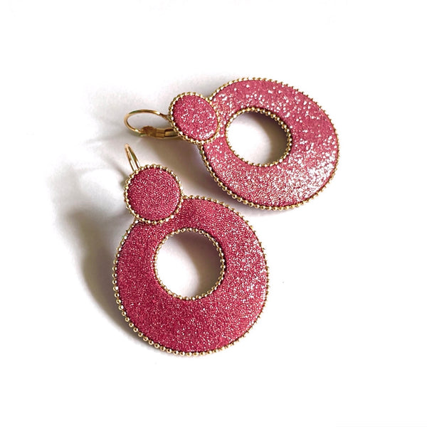 boucles d'oreilles créoles Nune modèle Céleste en forme de cercles en cuir framboise pailletée argent cerclées de chaîne dorée, sur fond blanc