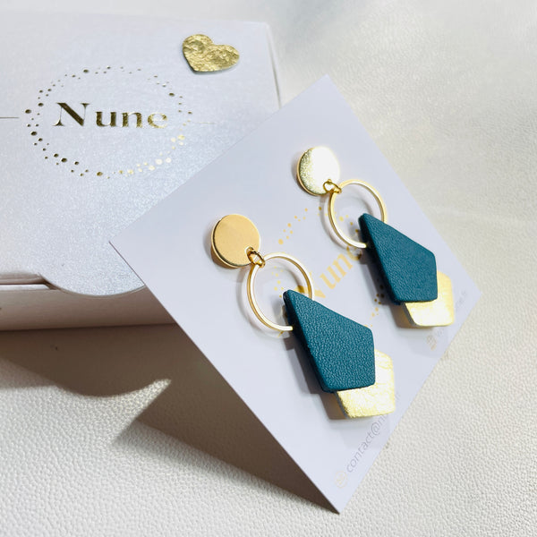 NUNE puces d'oreilles dorées Sagittis, pendentifs en duo de losanges en cuir recyclé vert canard et doré, sur fond blanc avec boîte cadeau Nune