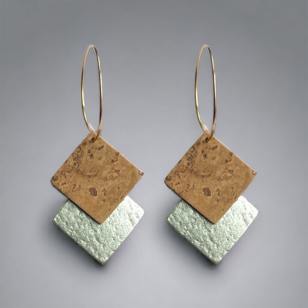 Boucles d'oreilles créoles dorées en liège doré antique et argenté. Forme géométrique double-losanges imbriqués, sur fond gris