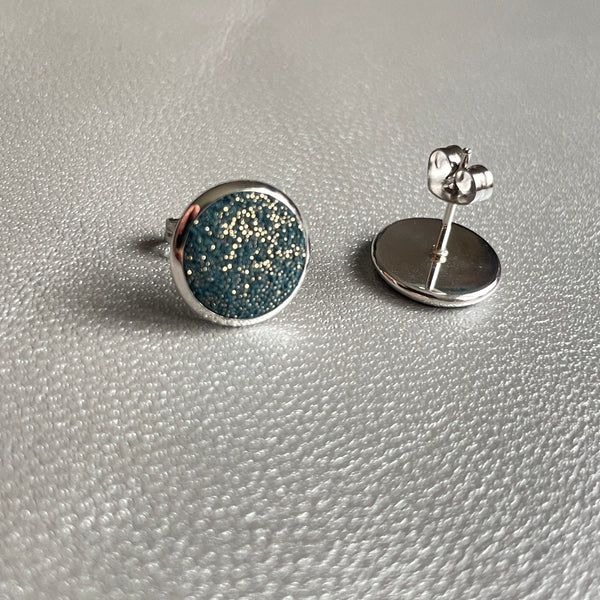 Puces d'oreilles argentées rondes Nune modèle Ilis argenté pailleté avec pastilles de cuir vert canard pailleté or, sur fond de cuir gris métallisé