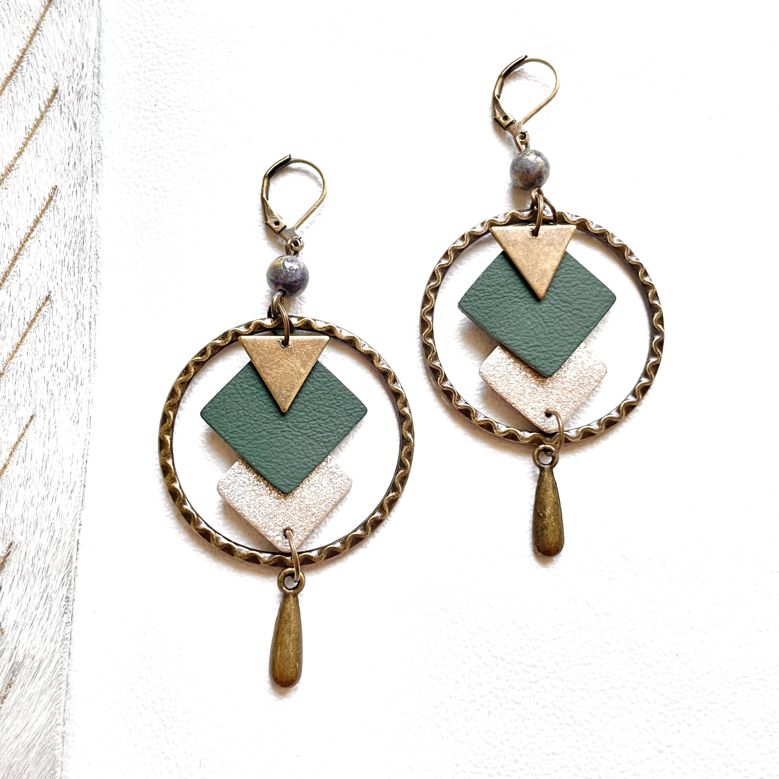 Boucles d'oreilles en bronze Nune modèle Adamante Créoles en cuir vert sapin e forme de losange sur fond blanc