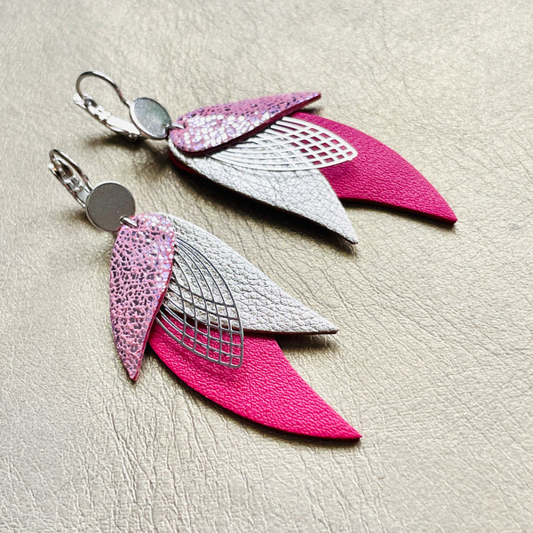 Boucles d'oreilles argentées Nune en forme de plumes, modèle Ara en cuirs rose brillant, argent et fushia sur fond blanc