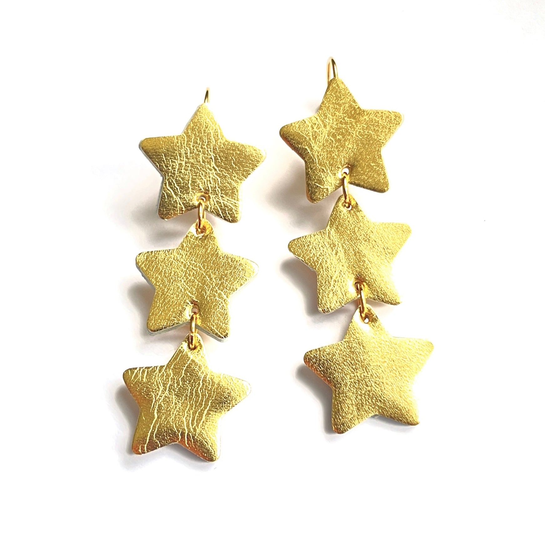 NUNE Boucles d'oreilles Starlight, chapelet d'étoiles en cuir recyclé doré, sur fond blanc vues de dessus