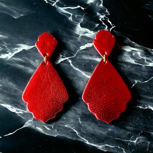paire de boucles d'oreilles rouge métallisé de style rétro baroque, sur fond marbre noir