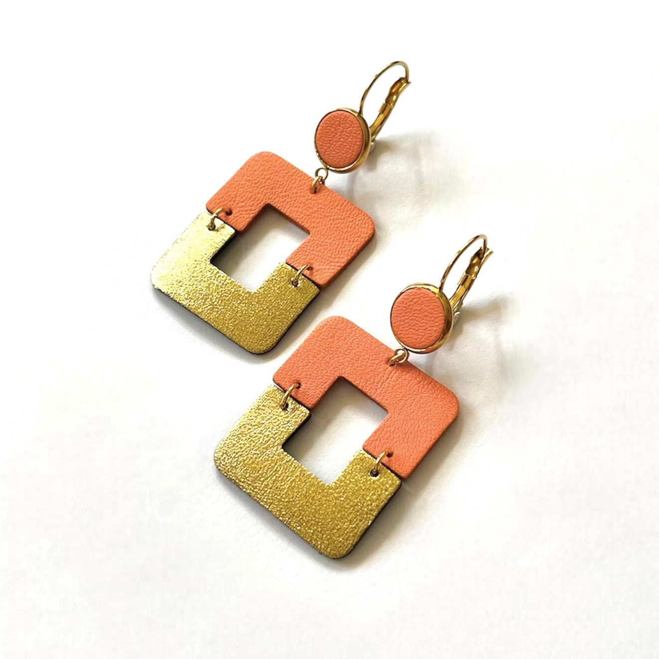 NUNE boucles d'oreilles Ekta dorées avec cabochon en cuir vert canard et duo de losanges en cuir recyclé saumon clair et doré satiné, vues de biais, sur fond blanc