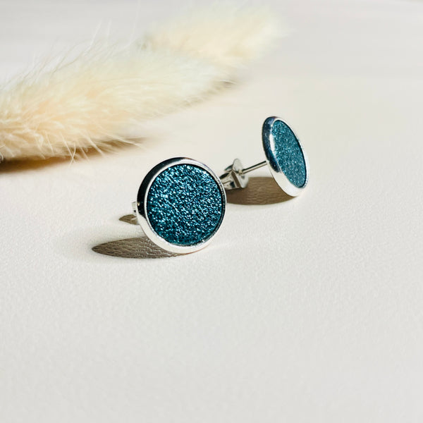 Puces d'oreilles argentées rondes Nune modèle Ilis argenté avec pastilles de cuir saphir pailleté, sur fond de cuir blanc cassé