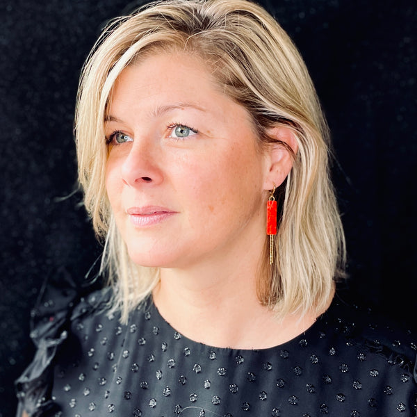 Boucle d'oreille Effinis de Nune, dorée à l'or fin avec cuir marin, cuir de poisson saumon rouge cardinal, de forme effilée avec chaînettes dorées pendantes, portée à l'oreille