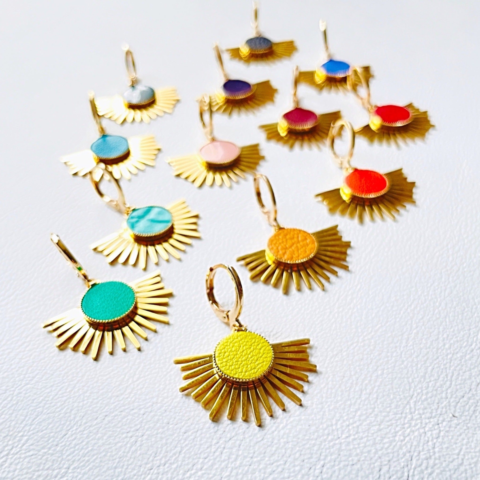 Petites boucles d'oreilles dorées Nune modèle Miria en acier inoxydable et laiton doré à l'or fin avec sertis en cuir de toutes les couleurs, sur fond blanc