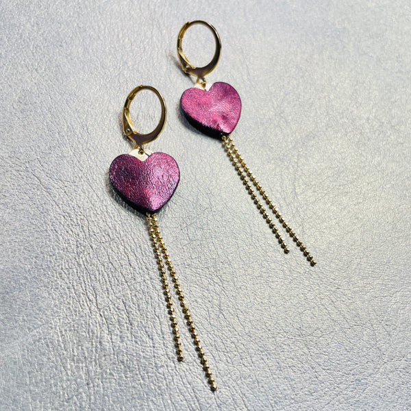NUNE fines boucles d'oreilles dorées, petits cœurs de cuir recyclé grenat métallisé et chaînettes, sur fond gris