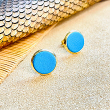 Charger l&#39;image dans la galerie, Puces d&#39;oreilles dorées rondes Nune modèle Ilis avec cuir bleu turquoise, sur fond de cuirs beige
